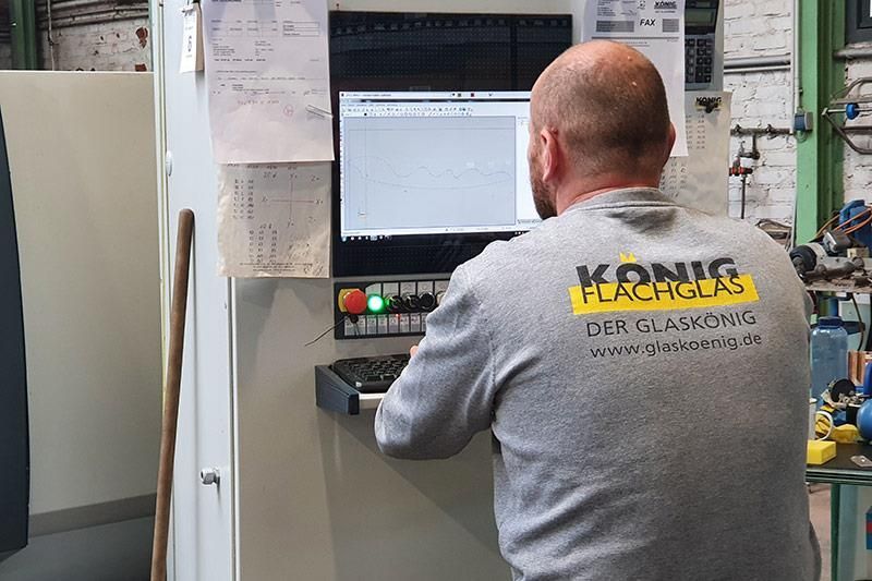 Ein Mann in einem Hemd von König Machining arbeitet an einem Computer.