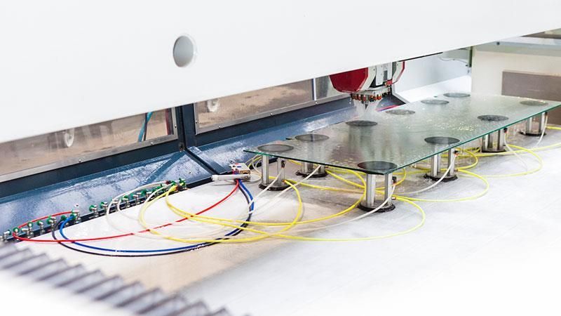 Eine Maschine schneidet ein Stück Papier, aus dem Drähte herauskommen.