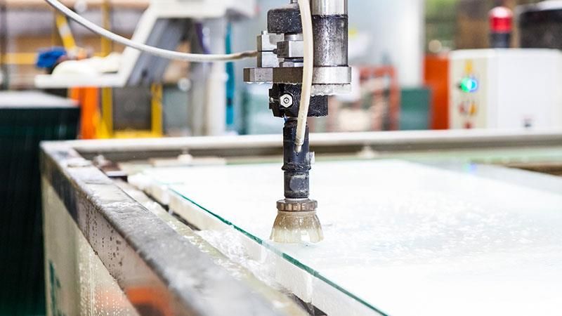 In einer Fabrik schneidet eine Maschine ein Stück Glas.