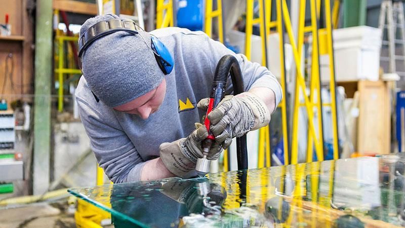 Ein Mann arbeitet in einer Fabrik an einem Stück Glas.