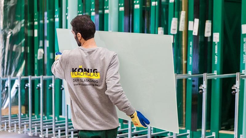 Ein Mann trägt ein großes Stück Glas und auf seinem Hemd steht König