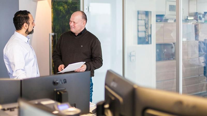 Zwei Männer stehen in einem Büro und unterhalten sich