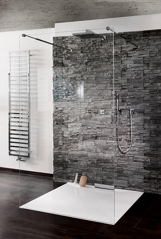 Ein Badezimmer mit ebenerdiger Dusche und einer Ziegelwand