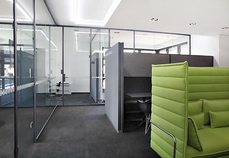 Ein Zimmer mit einer grünen Couch und einem Schreibtisch