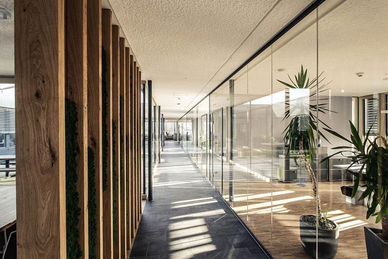 Ein langer Flur mit Glaswänden und Holzsäulen