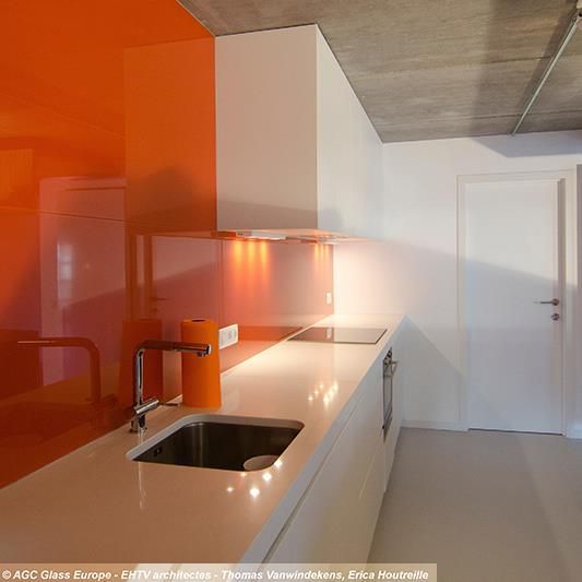 Eine Küche mit orangefarbenen Wänden und weißen Arbeitsplatten