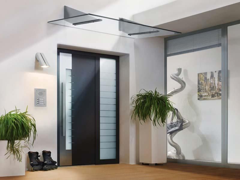 Ein Flur mit einer schwarzen Tür und einem Glasvordach