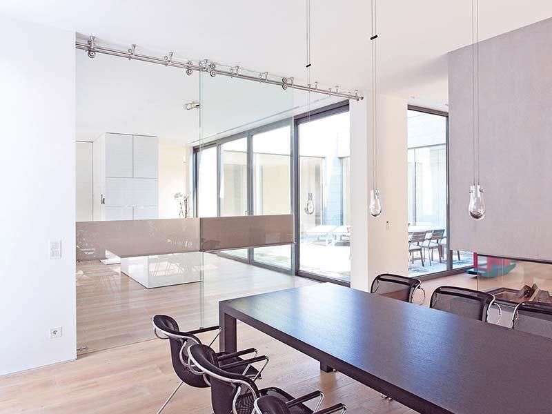 Ein Esszimmer mit Tisch und Stühlen und vielen Fenstern.