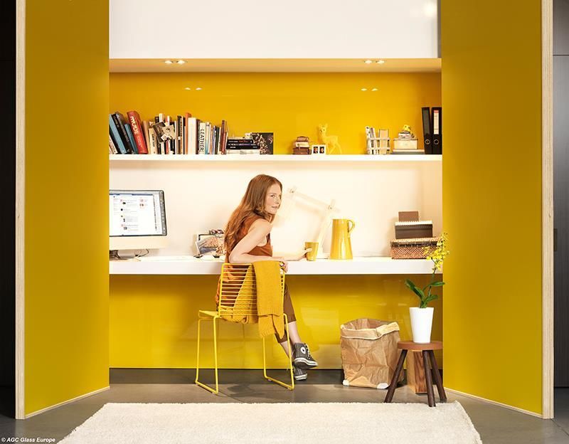 Eine Frau sitzt an einem Schreibtisch in einem gelben Raum