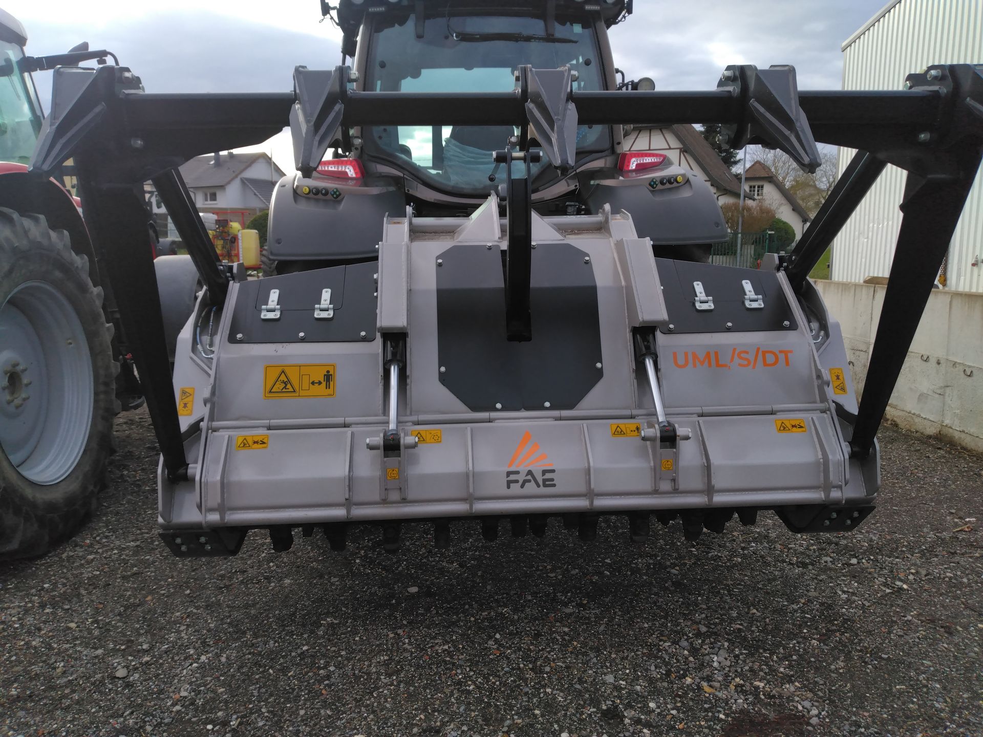 Tracteur gris équipé d'un broyeur, en extérieur.