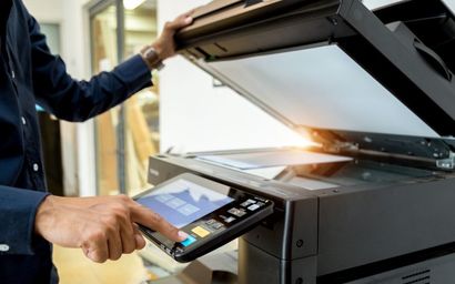 Un hombre está usando una impresora para escanear un documento.
