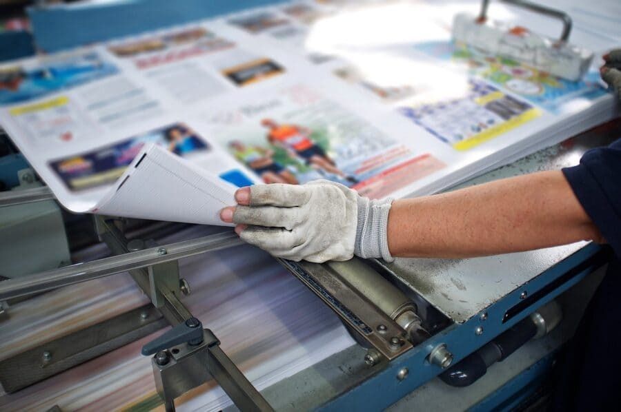 Una persona sostiene un trozo de papel delante de una máquina de impresión.