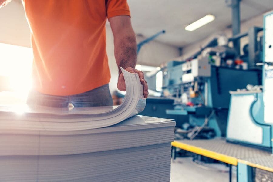 Un hombre sostiene una pila de papeles en una fábrica.