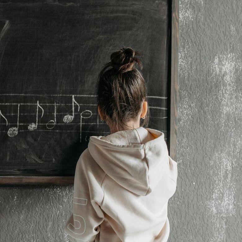 Alumnita escribiendo notas musicales en la pizarra