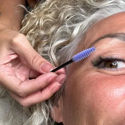 Mujer recibiendo maquillaje aplicado por otra mujer en un estudio.