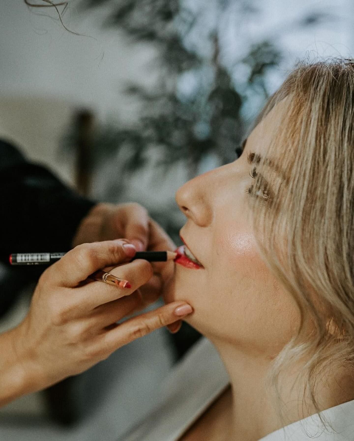 Maquilladora aplica lápiz labial en los labios de una mujer, vista de cerca.