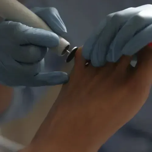 Mujer recibiendo maquillaje aplicado por otra mujer en un estudio.