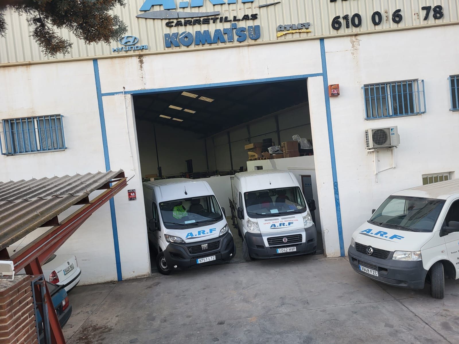 Tres furgonetas blancas están estacionadas frente a un edificio que dice Komatsu.