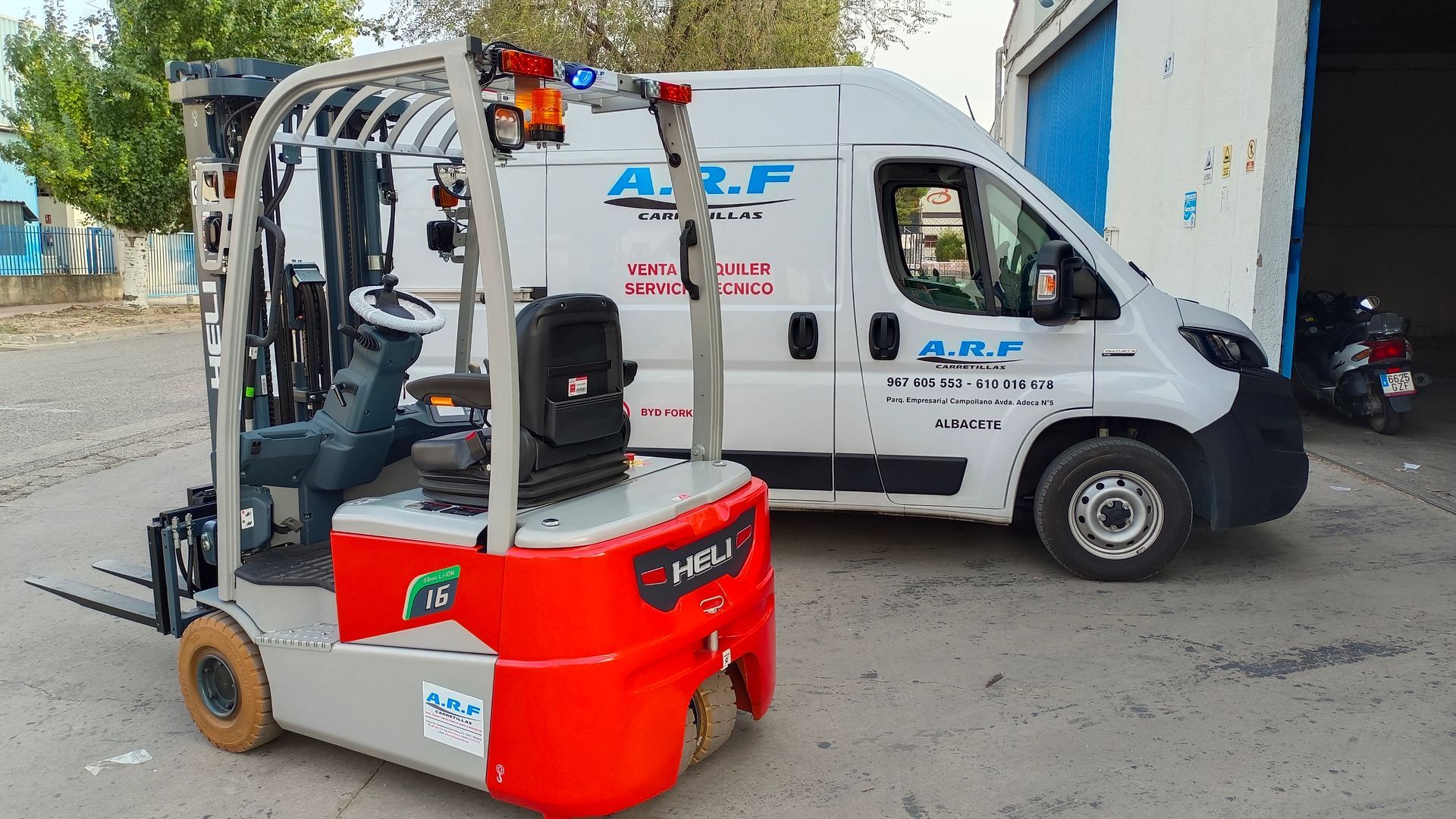 Una carretilla elevadora roja está estacionada al lado de una furgoneta blanca.