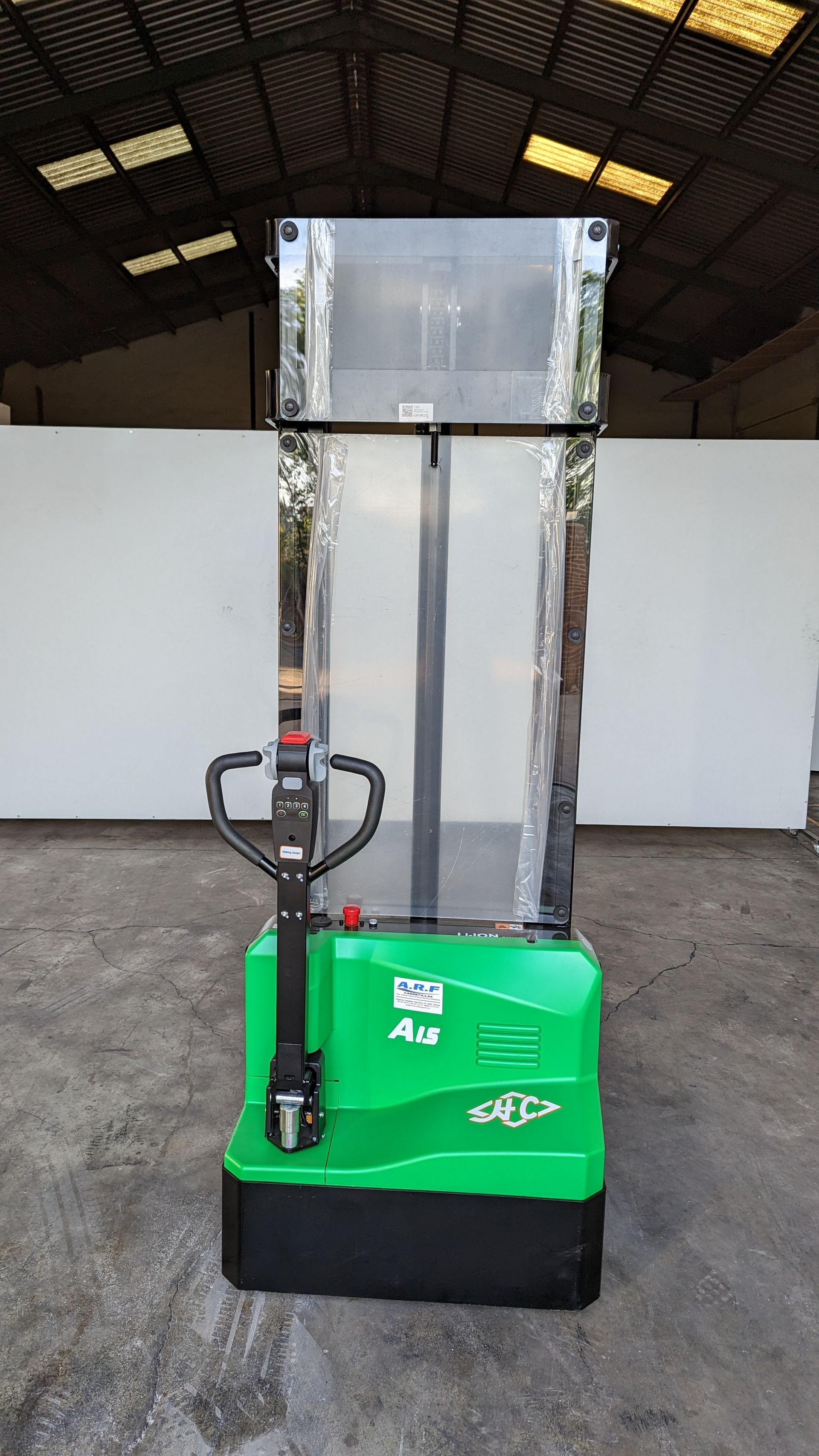 Una carretilla elevadora verde y negra está estacionada frente a un edificio.