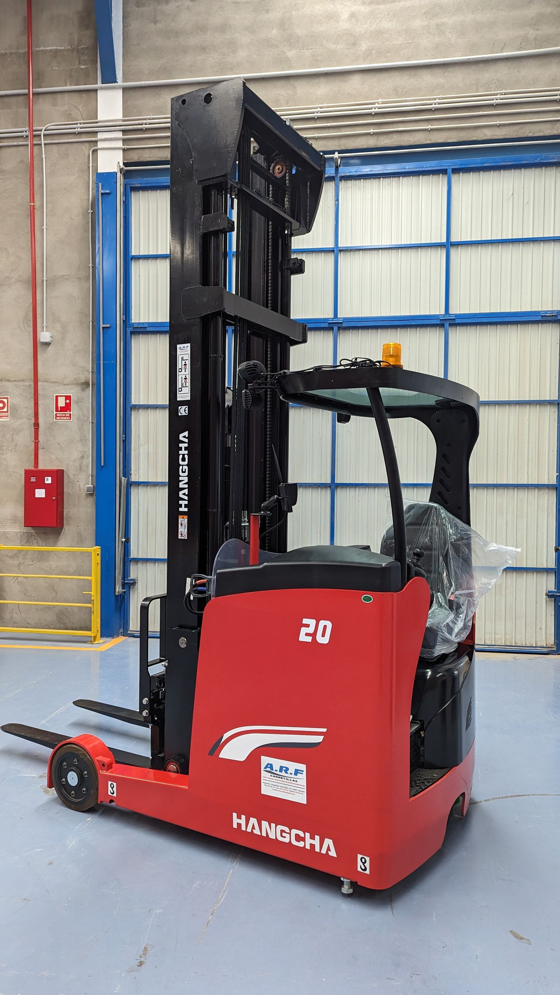 Una carretilla elevadora roja está estacionada en un almacén.