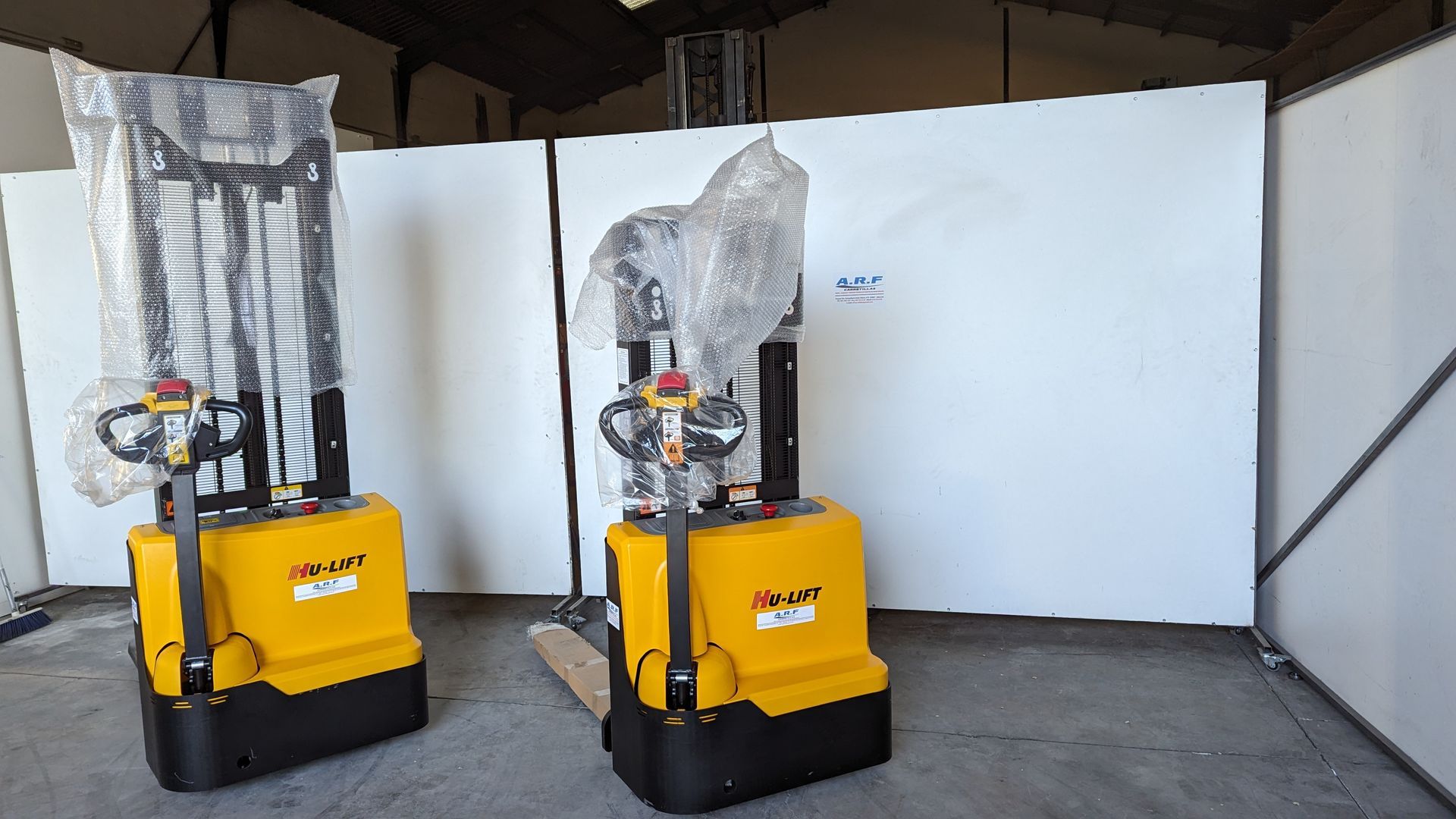 Dos carretillas elevadoras amarillas y negras están una al lado de la otra en un almacén.