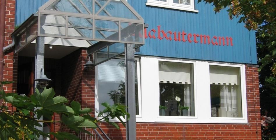 Eingang eines Gebäudes mit blauer und gemauerter Fassade; in roter Schrift steht „lebeautmann“.