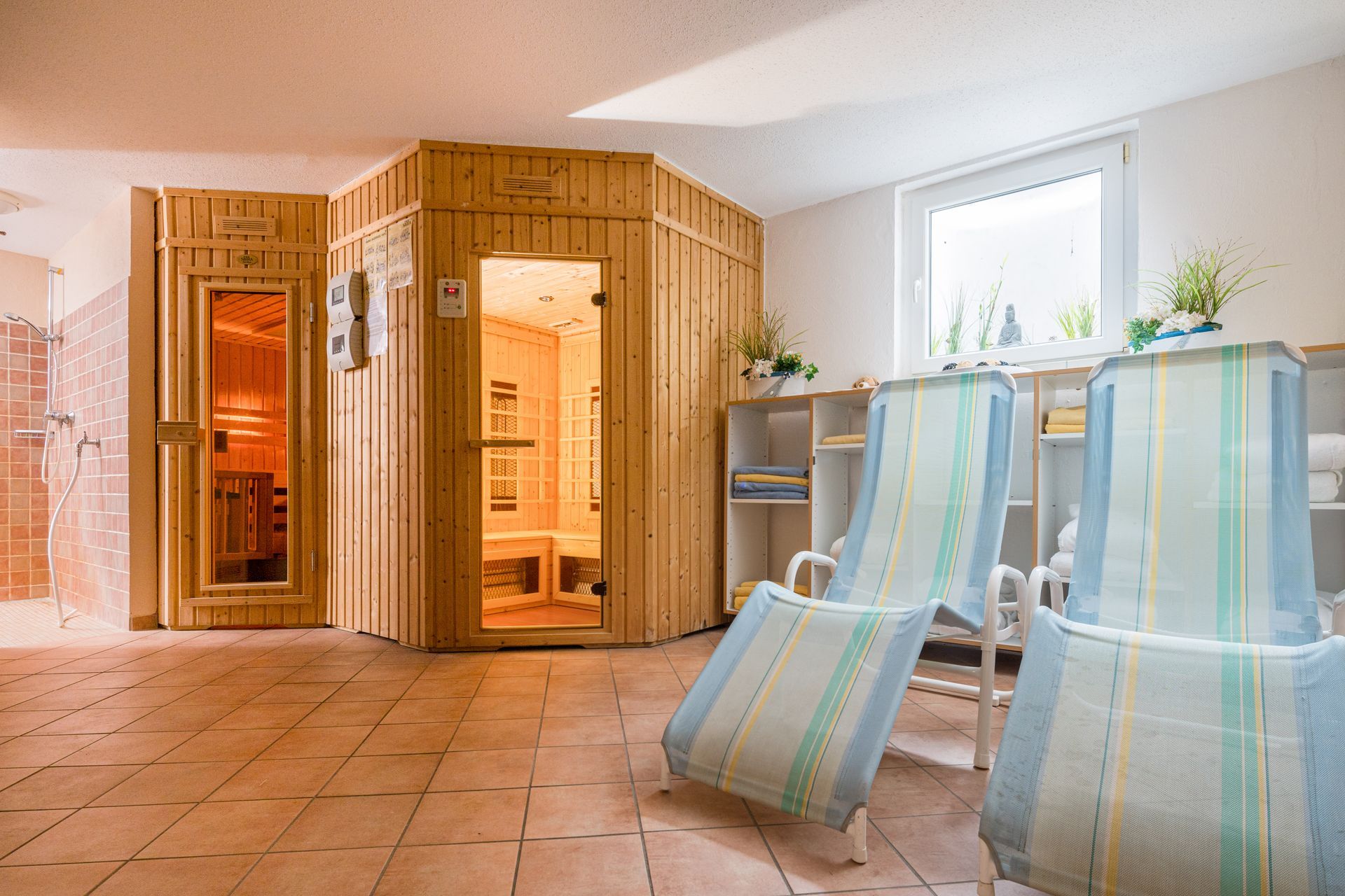 Sauna mit Holzinterieur, Liegestühlen und einem Fenster in einem Ruheraum.