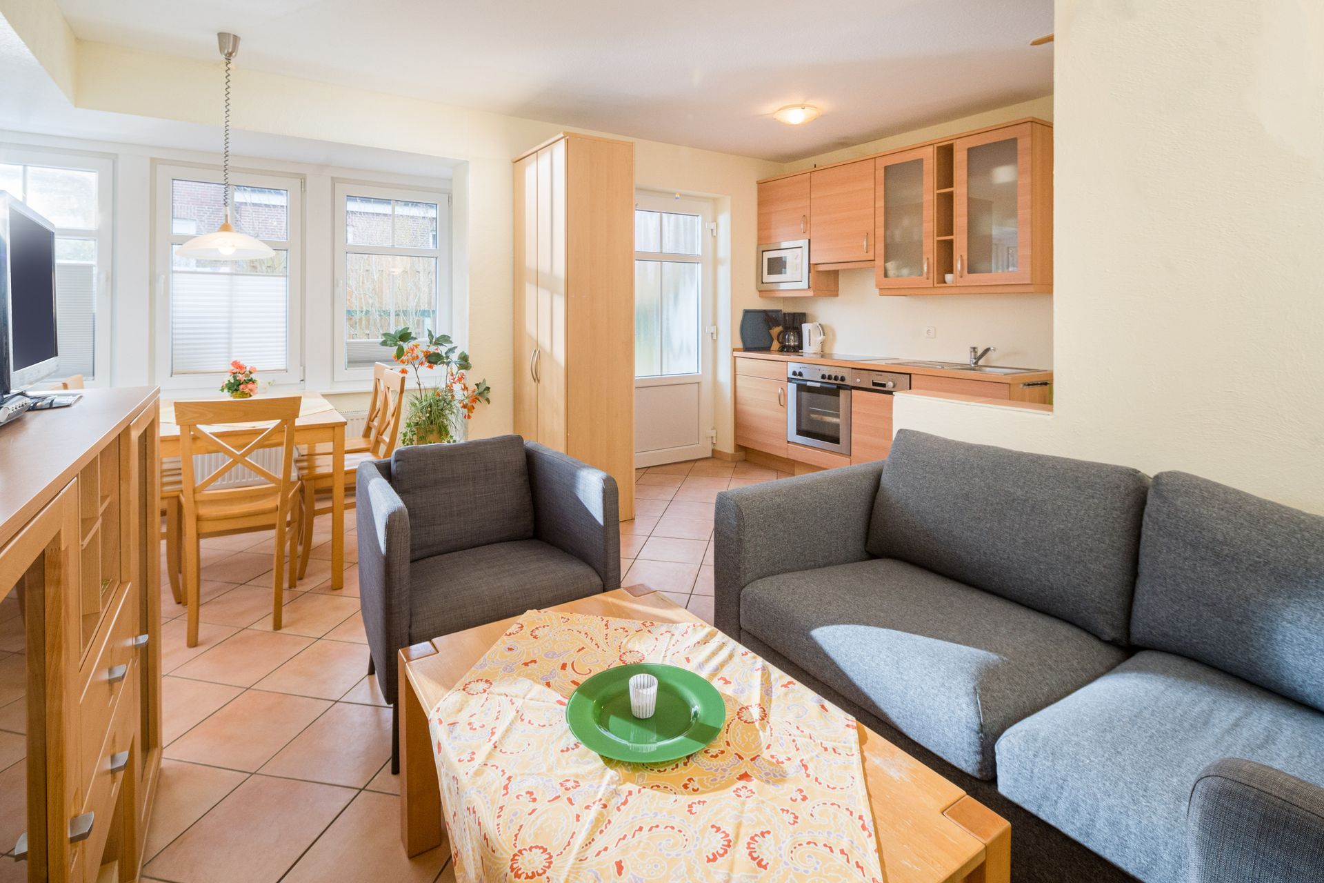 Gemütlicher Wohnbereich mit Küche mit Sofa, Sessel, Tisch und Essgruppe aus Holz, in der Nähe des Küchenbereichs.