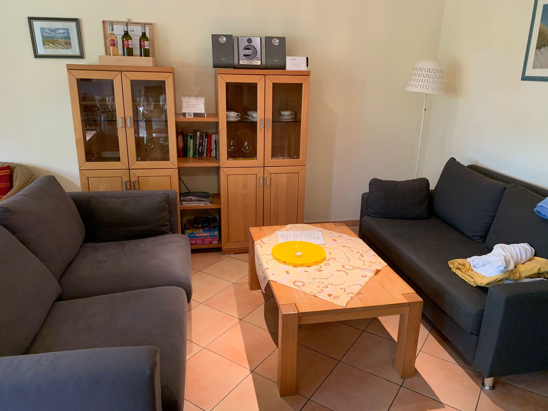 Wohnzimmer mit Holzmöbeln, grauen Sofas und einem Couchtisch.