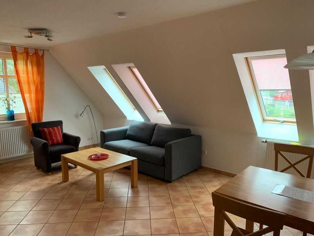 Wohnzimmer mit Sofa, Sessel, Couchtisch, zwei Dachfenstern und einem Esstisch.