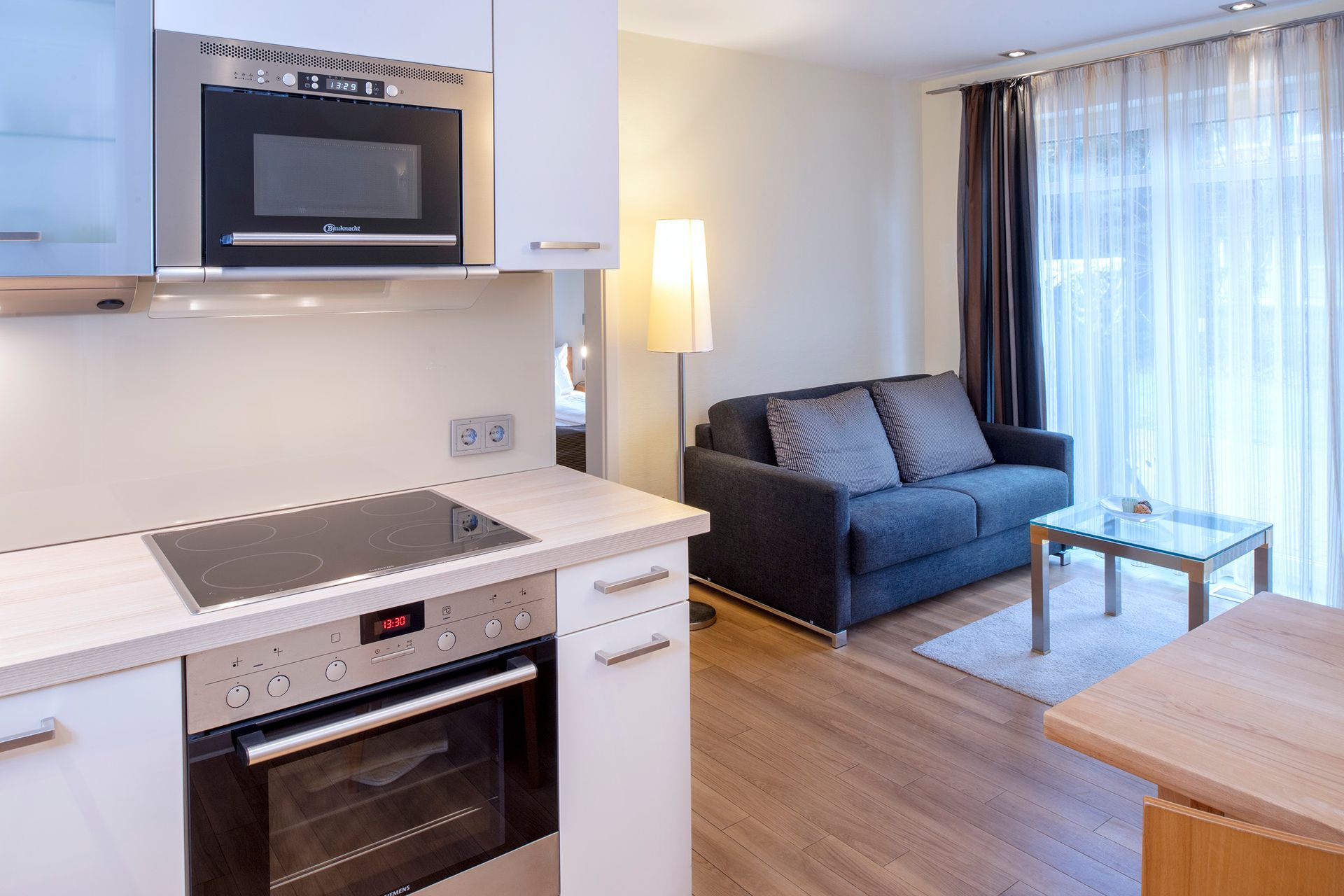 Moderne Küche und Wohnbereich mit Einbaubackofen und Sofa.