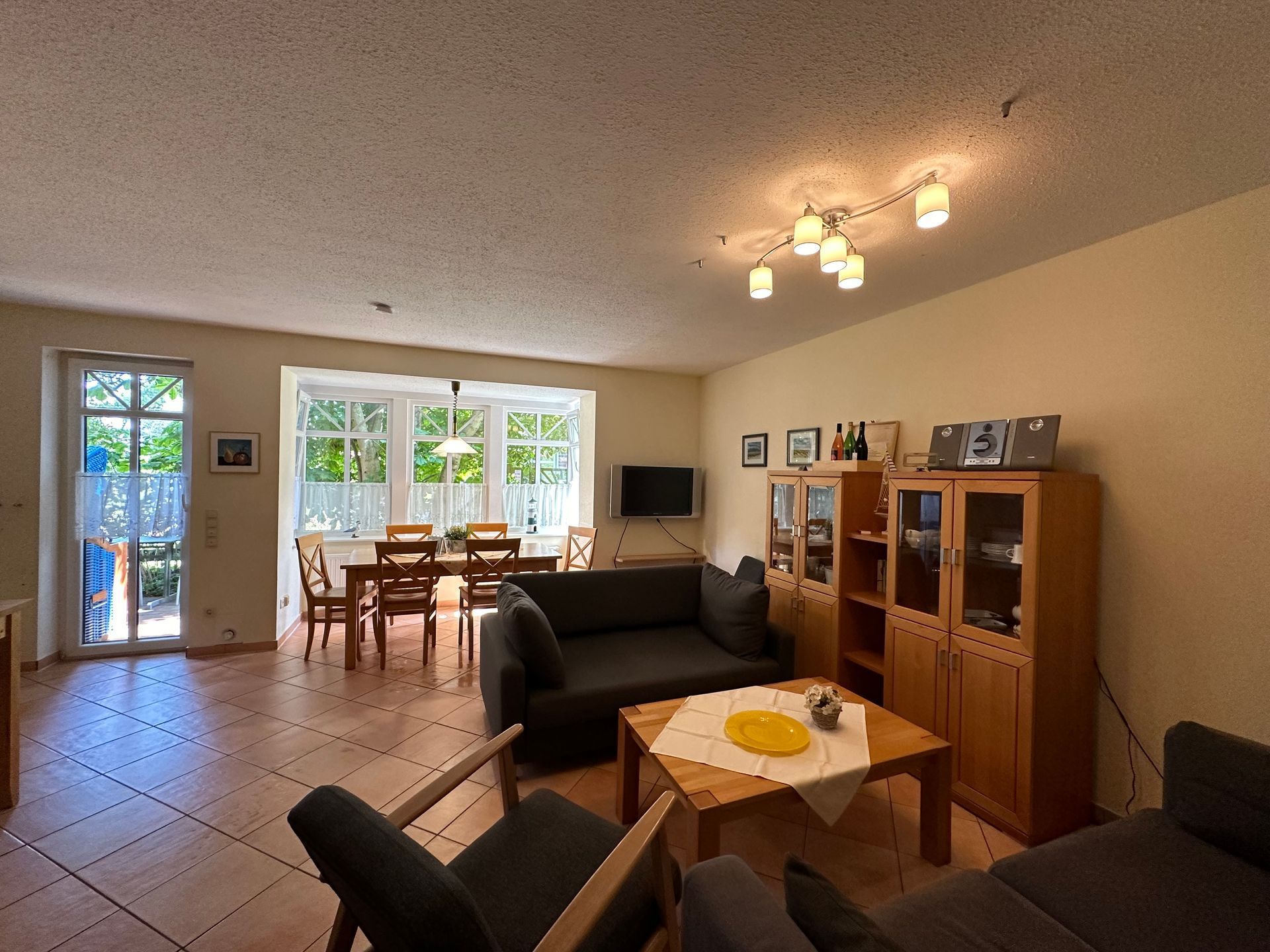 Wohnzimmer mit dunkelgrauen Möbeln, Holztisch und natürlichem Licht durch große Fenster.