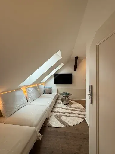 Une pièce vide avec fenêtres, plafonniers et radiateurs. Vue sur les arbres extérieurs.