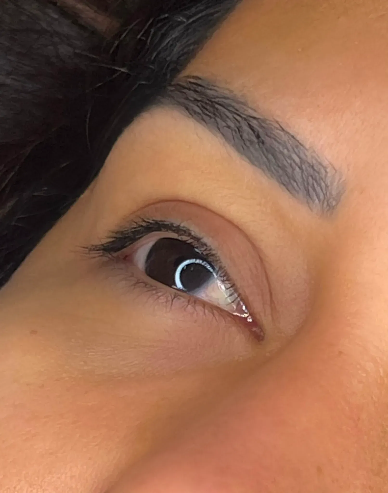Primer plano de un solo ojo con delineador de ojos alado, ceja arqueada y piel de tono cálido.