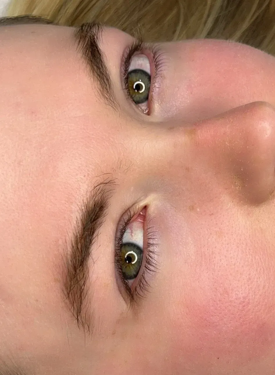Primer plano de un rostro con ojos verdes, cejas oscuras y mejillas sonrojadas, tumbado de lado.