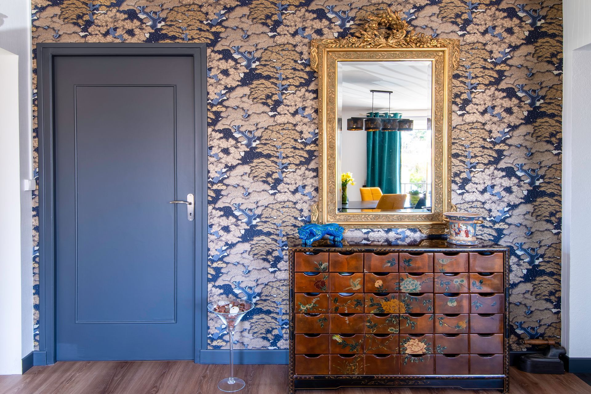 Papier peint floral bleu et doré sur mur avec porte bleue
