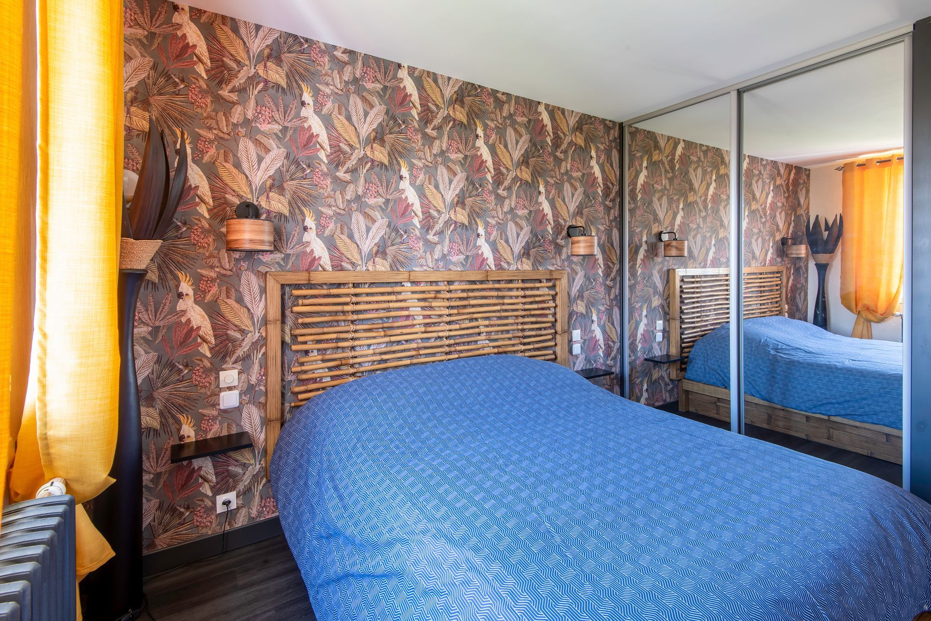 Chambre refaite avec du papier peint et un placard coulissant avec un miroir