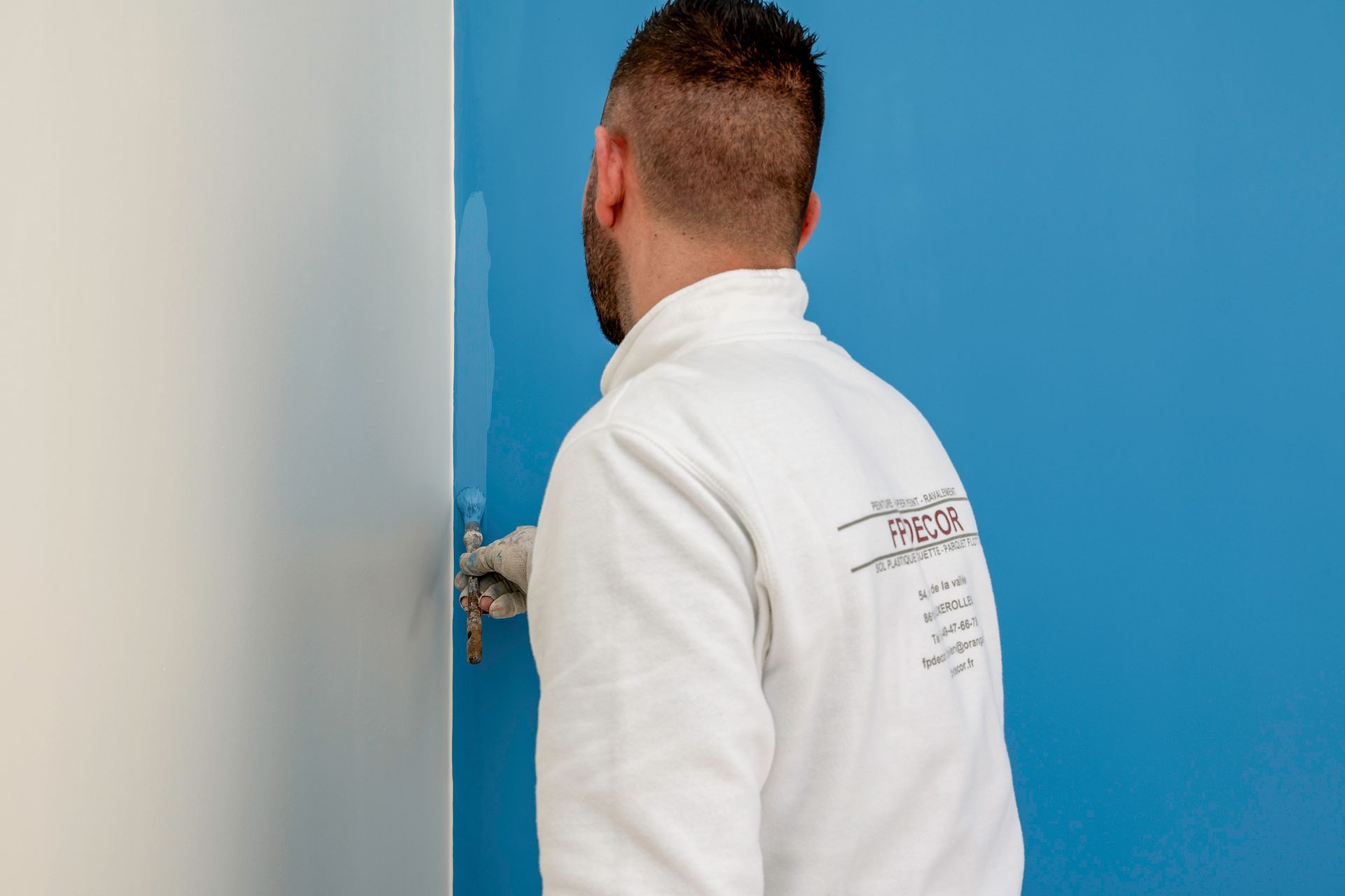 Artisan peintre en train de peindre un mur en bleu