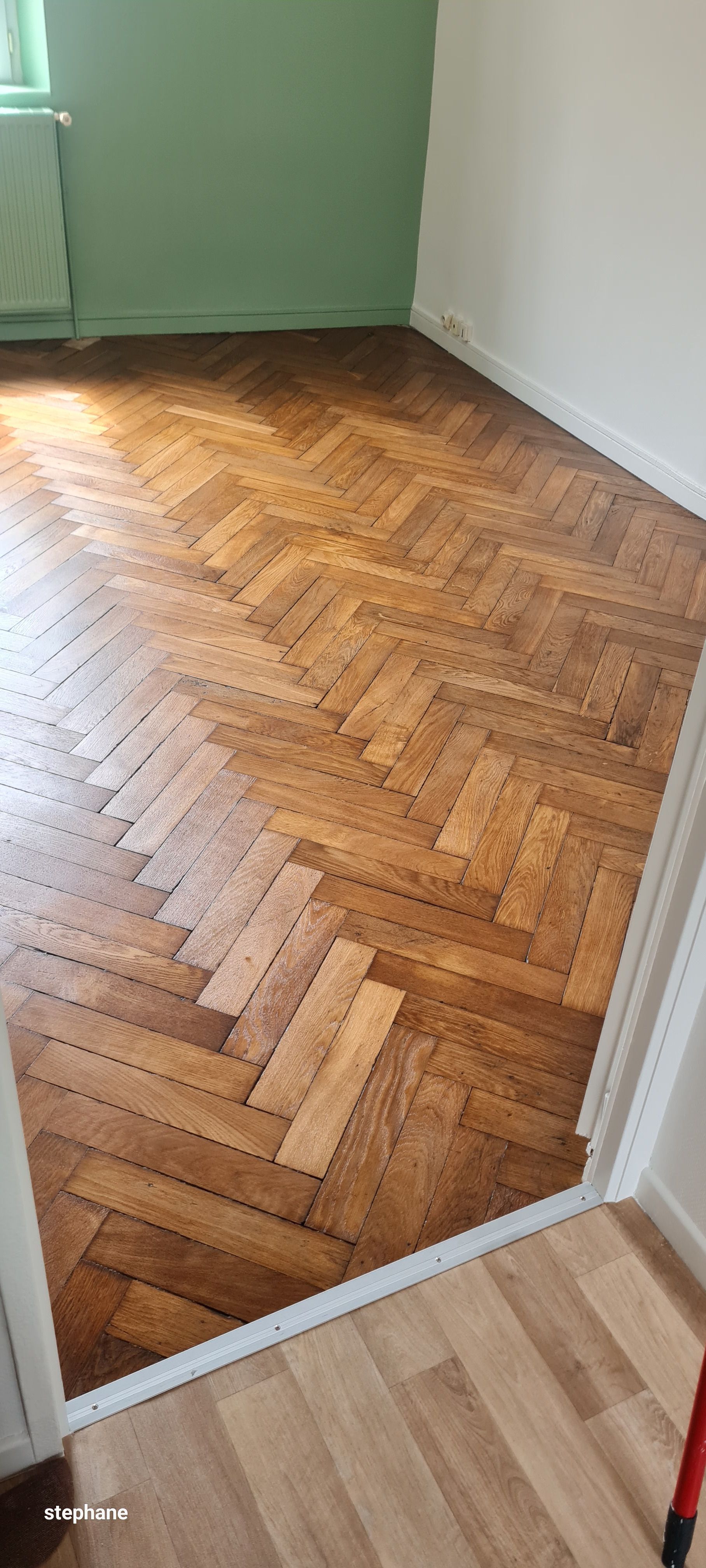 Parquet à chevrons dans une pièce aux murs et à l'encadrement de porte verts et blancs