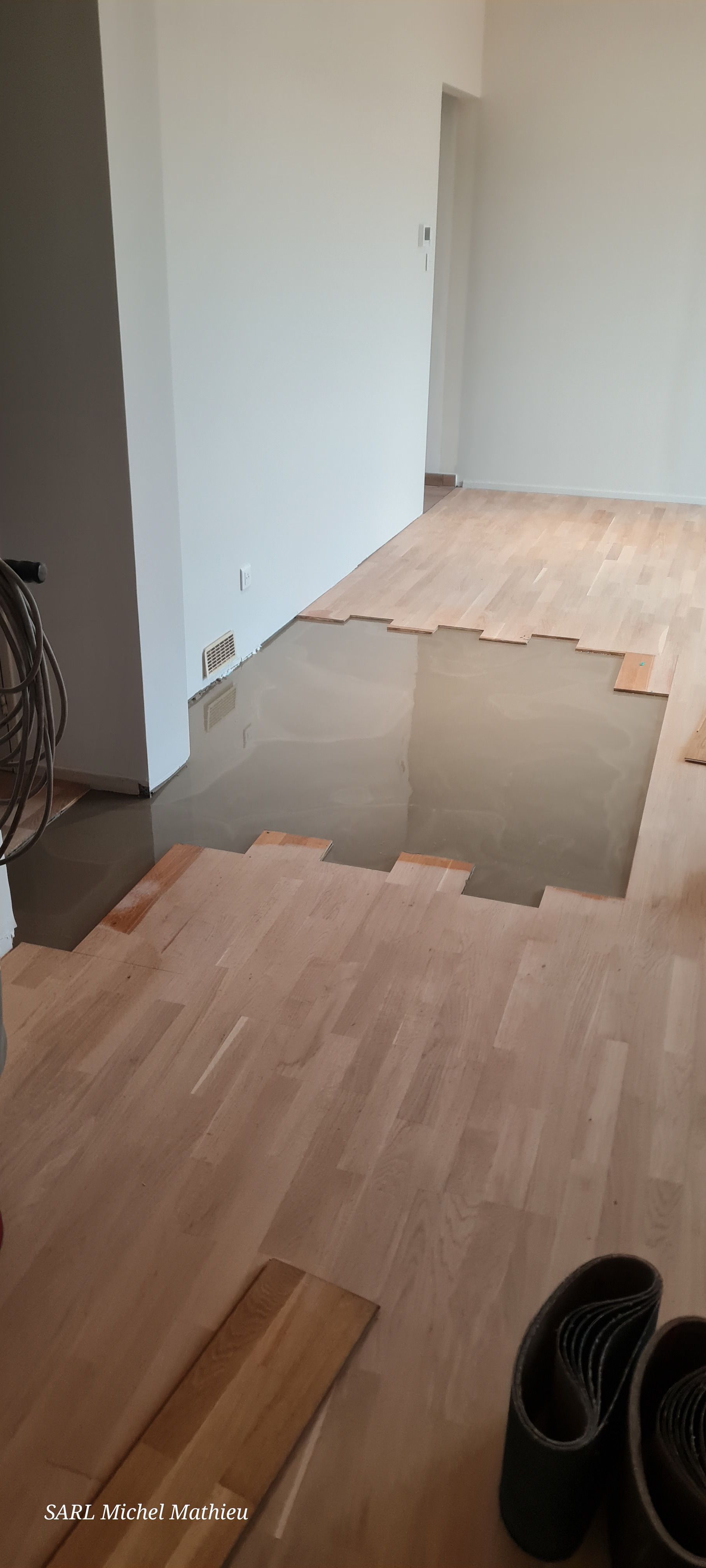 Pose d'un parquet dans une pièce, partiellement terminée