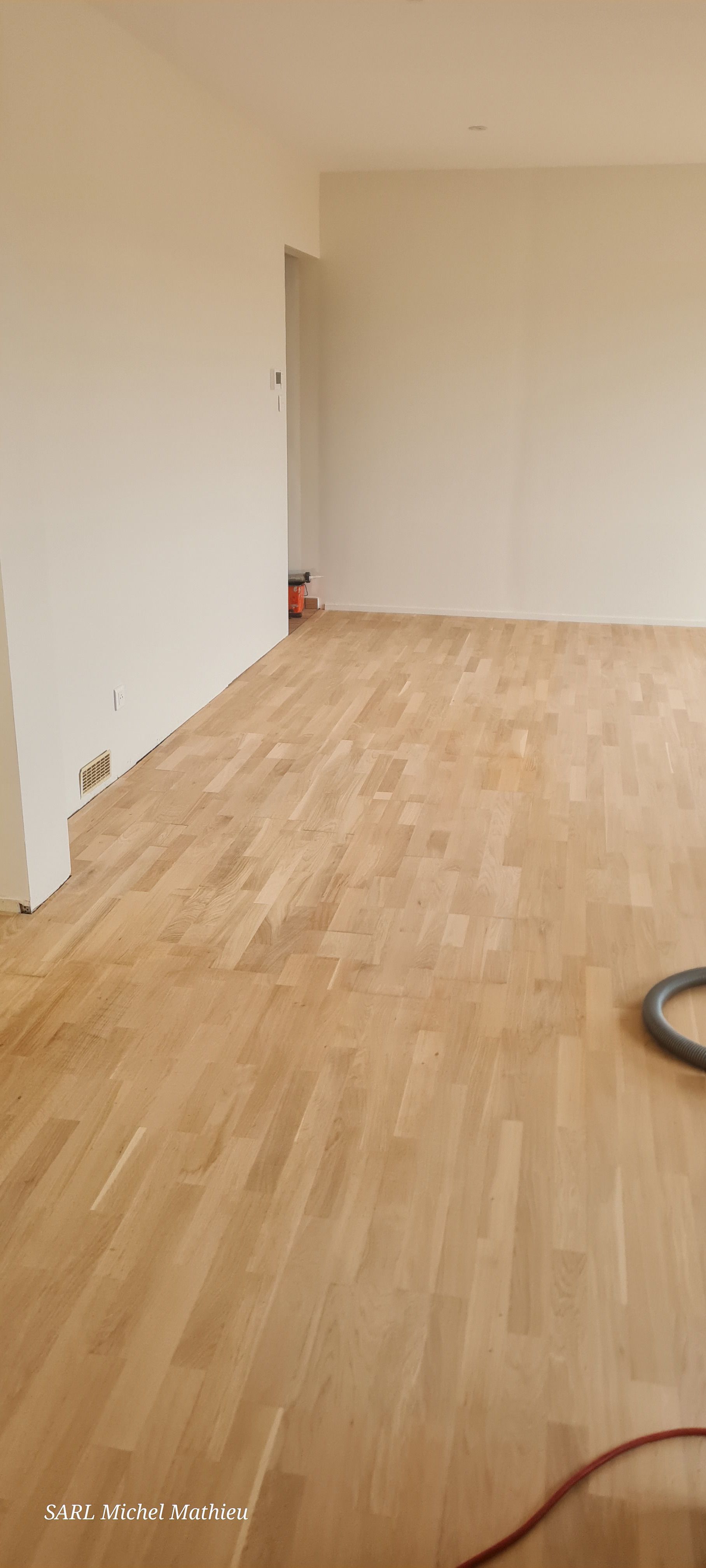 Sol en bois dans une pièce en rénovation avec des murs blancs