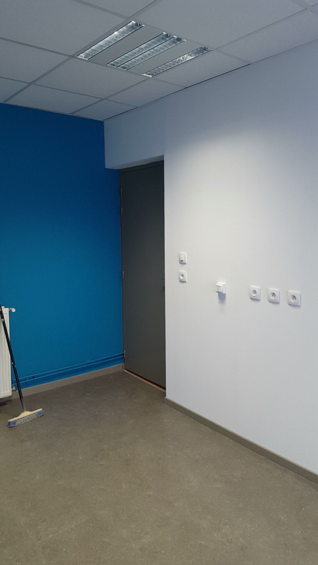 Intérieur d'une pièce aux murs bleus et blancs  avce une porte grise