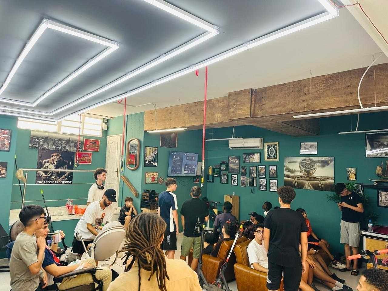 Personas en una habitación con paredes verdes e iluminación decorativa, algunos de pie, otros sentados.