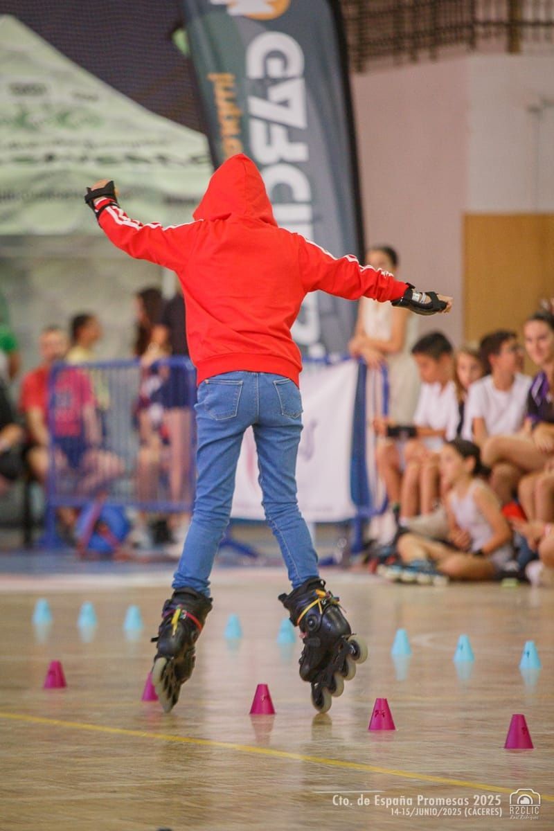 Persona con sudadera roja, patinando en patines y con los brazos extendidos, atravesando conos en una competición.
