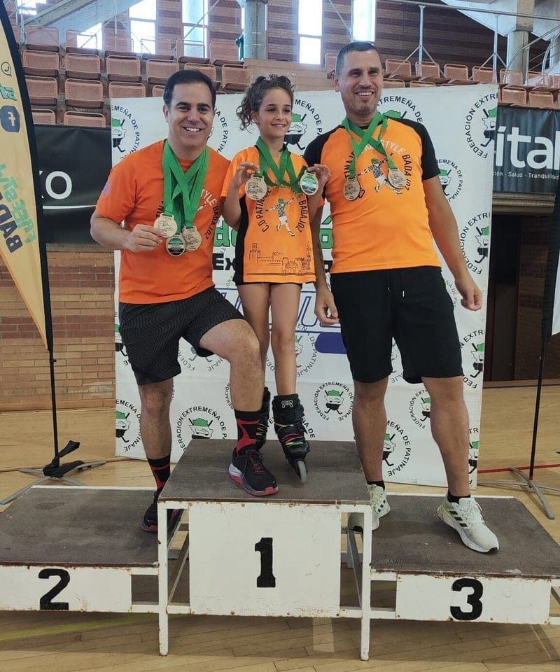 Tres personas en un podio tras una competición de patinaje sobre ruedas. 