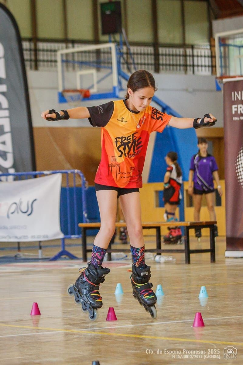 Niña en patines en línea haciendo equilibrio entre conos en un piso de madera, con los brazos extendidos.