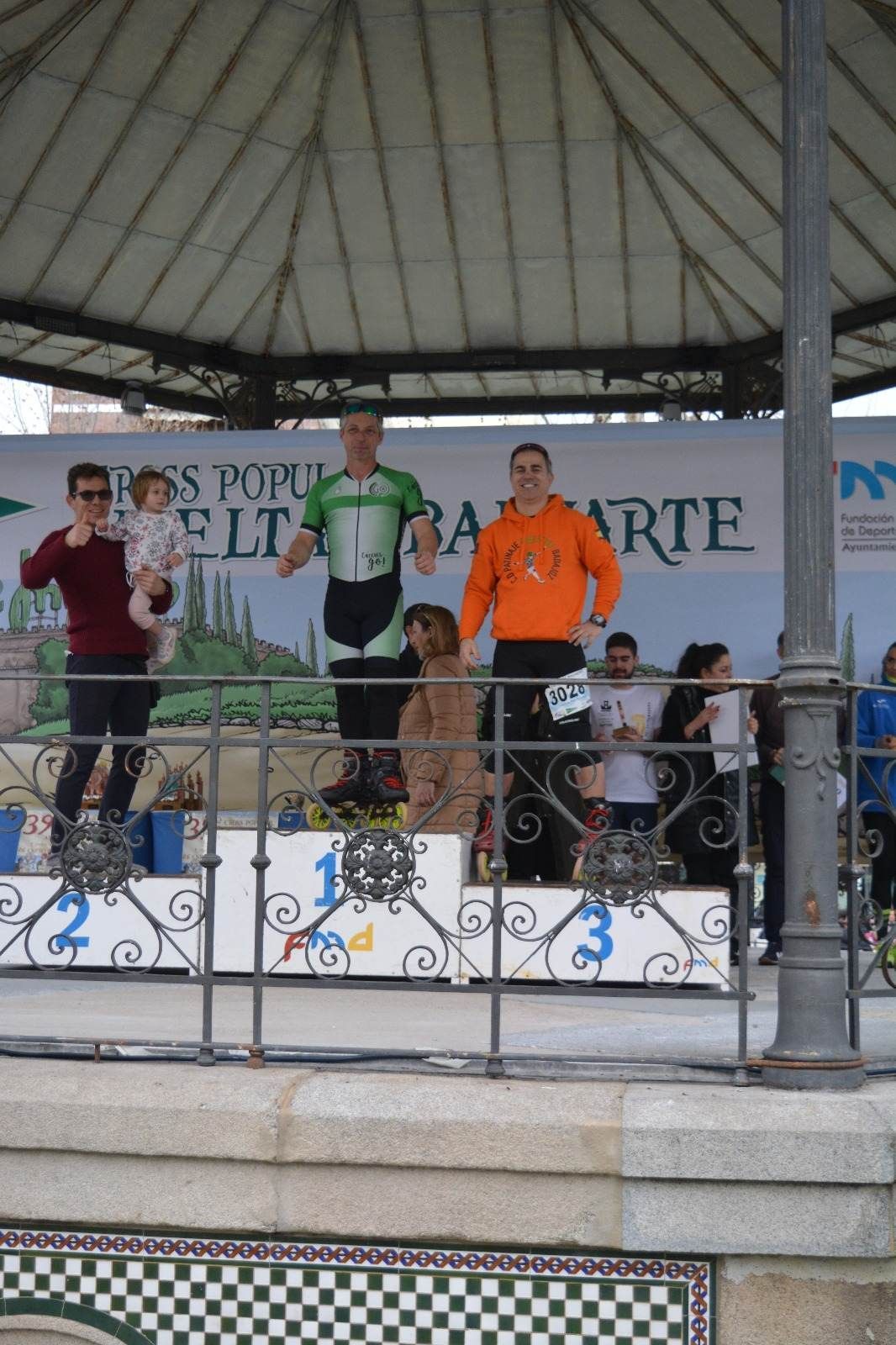 Podio con tres hombres, un niño y un perro celebrando una victoria en una carrera.