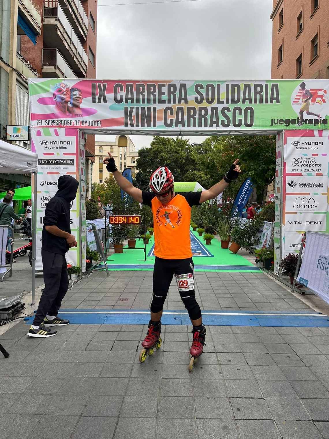 Hombre en patines con los brazos en alto cruza la meta. Pancarta 