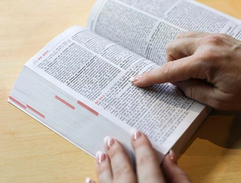 Doigt féminin pointé sur une ligne d'un livre de texte de lois
